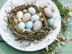 Rustikales Nest aus bemoosten Zweigen mit Heißkleber bauen, mit Moos auspolstern und mit Eiern füllen.