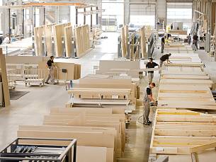 An großen Produktionstischen fertigen Handwerker und Mechaniker bis zu rund 12,50 Meter große Bauteile, meist in Holz-Tafelbauweise.