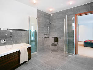 Viel Platz im Bad, um sich mit einem Rollstuhl zu bewegen. Eine großzügige Walk-in-Dusche sorgt für Komfort.