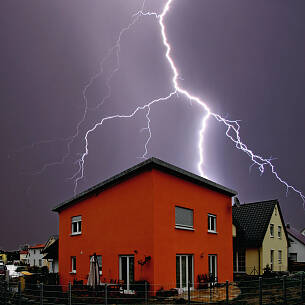 Ein Blitzeinschlag in der näheren Umgebung überträgt sich die hohe Spannung sowohl über Strom- als auch über Antennen- und Telefonleitungen.