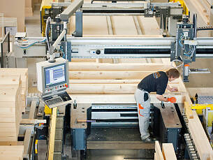 An großen Produktionstischen fertigen Handwerker große Bauteile, meist in Holz-Tafelbauweise.