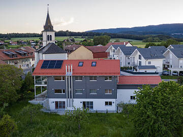 Das moderne Gebäude mit drei Wohneinheiten fügt sich harmonisch neben ihrem alten Bauernhaus in die Landschaft.